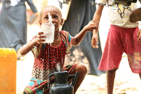Glad liten flicka fyller på en vattenflaska