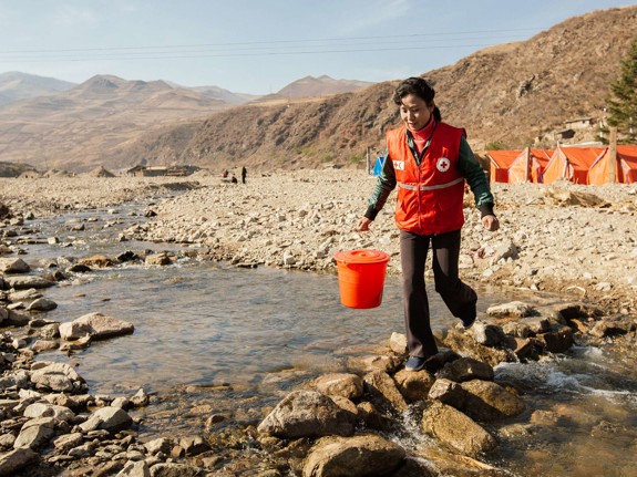 Röda Korsets volontär i Nordkorea går över vattendrag.